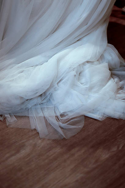 White wedding dress fabric gathered on a wooden floor, creating delicate texture