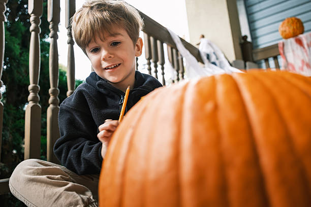 istock Young boy sketching on pumpkin for Halloween 2243458668