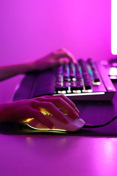 istock Close-up of hands playing on a computer keyboard and mouse in pink LED lighting. Modern gaming setup with neon glow and cyber aesthetic. 2243460256