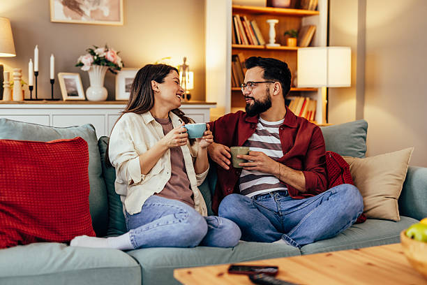 istock Couple relaxing on sofa, drinking coffee and talking 2243460441