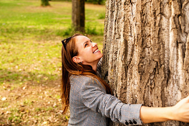 istock Happy urban woman hugging tree trunk outdoors connecting with nature 2243462852