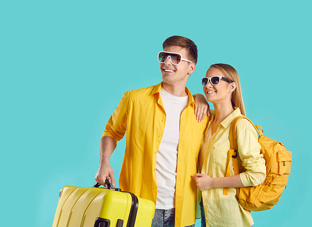 istock Two happy tourists with suitcase and backpack looking at copy space on turquoise background 2243463138