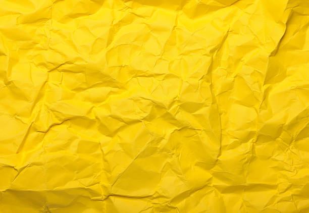 Crumpled yellow paper creates a textured background, displaying various wrinkles, folds, and creases across its surface, suitable for advertising and graphic design