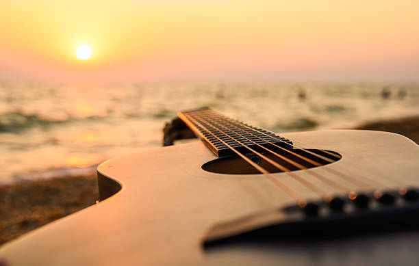 istock An acoustic guitar against a seaside sunset. Close-up, selective focus on the strings. 2243464305