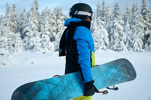 istock Snowboarder standing in a snowy forest holding a snowboard, basking in the winter tranquility and preparing for an outdoor adventure in the pristine wilderness. 2243472691