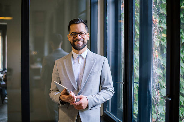 istock Businessman smiling, holding digital tablet in modern office 2243477634