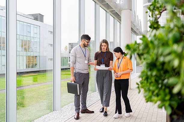 istock Diverse business professionals having informal meeting, discussing papers while walking in bright corporate corridor 2243478876