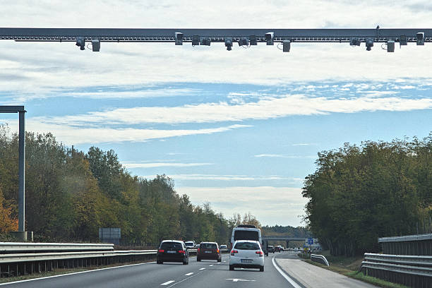 istock Traffic on a highway passes beneath a large overhead metal gantry supporting multiple cameras and sensors for electronic toll or speed monitoring 2243479573