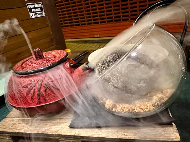 Teapot releasing smoke into a glass bowl containing food on a wooden surface