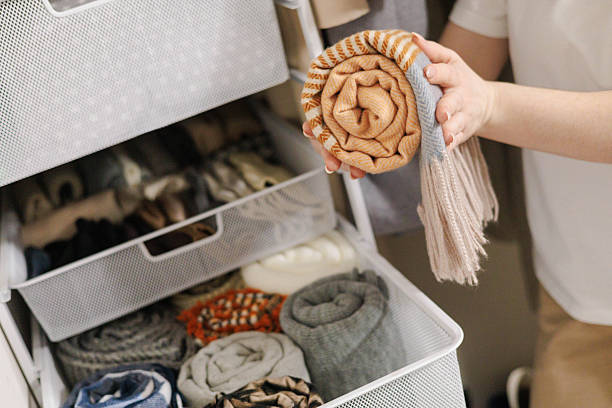 istock Hands placing rolled knitwear into mesh drawer — tidy minimalist closet storage and order 2243482382