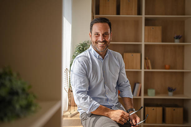 istock Smiling man holding glasses at home office 2243485191