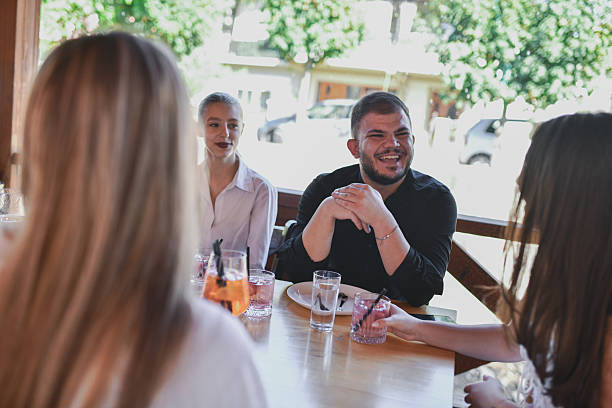 istock Friends Laugh and Chat At Outdoor Cafe Table Sharing Drinks and Good Conversation 2243485301