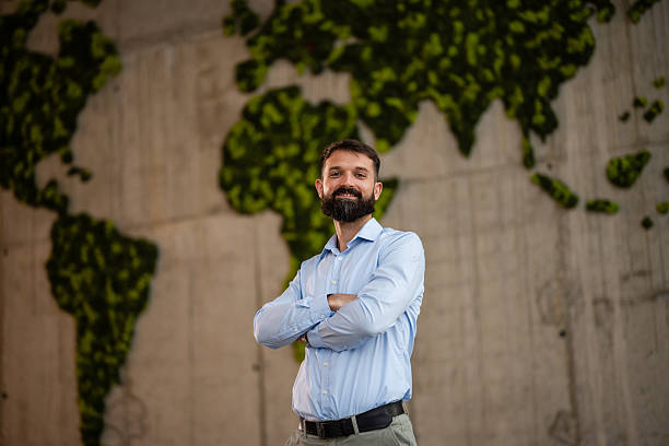 istock Businessman smiling, standing in front of world map 2243489242
