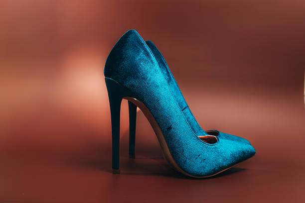 Close-up view of sophisticated light gray suede bridal pumps with pointed toes and stiletto heels, photographed against a warm-toned textured background. These elegant wedding shoes showcase minimalist design and luxurious materials, perfect for a bride's special day. The soft, matte finish of the suede material adds a touch of understated luxury, while the classic silhouette ensures timeless appeal. The neutral color palette and refined styling make these shoes a versatile choice for modern bridal fashion.