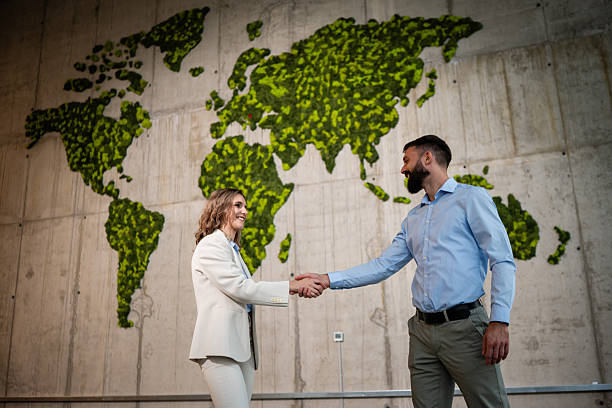 istock Business partners shaking hands on green world map background 2243489355
