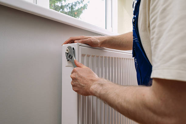 istock Plumber maintains residential radiator for efficient home heating 2243489480