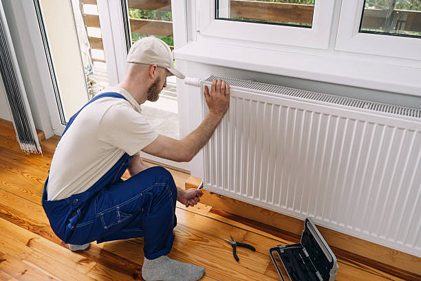 istock Man performs maintenance on a radiator in a modern living room during winter 2243489482