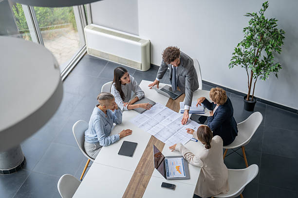 istock Business team analyzing blueprints during meeting in modern office 2243493381
