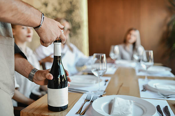 istock Wine Bottle Opening At Elegant Restaurant Table With Friends, Glasses And Dinner Setting 2243502520
