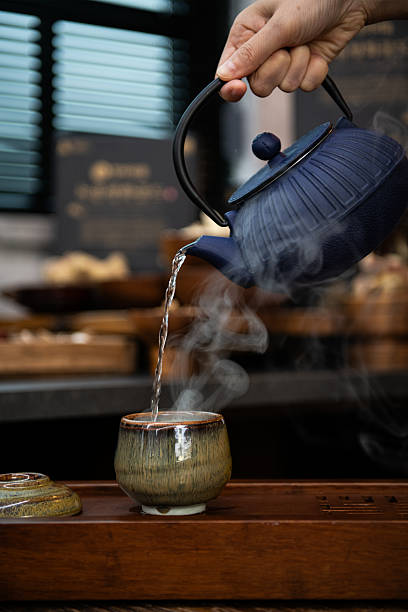 istock Hand Pouring Hot Water into a Steaming Tea Cup 2243505740