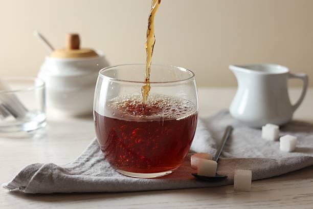 istock Pouring warm tea into cup on white wooden table, closeup 2243510251