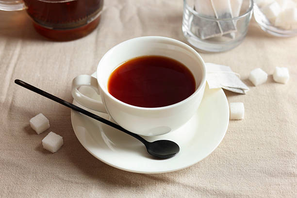 istock Tasty tea in cup and sugar cubes on light table 2243510260
