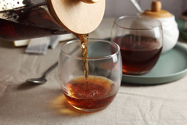 istock Pouring warm tea into cup on light table, closeup 2243510261