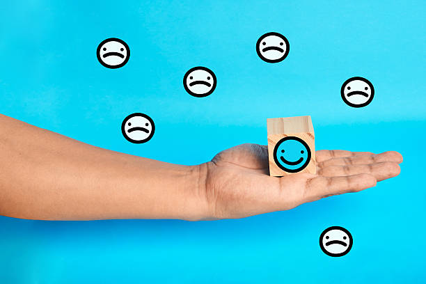 istock Hand presenting a happy choice among sad faces to represent customer satisfaction selection positive feedback and a service that solves problems and earns loyalty. 2243510824
