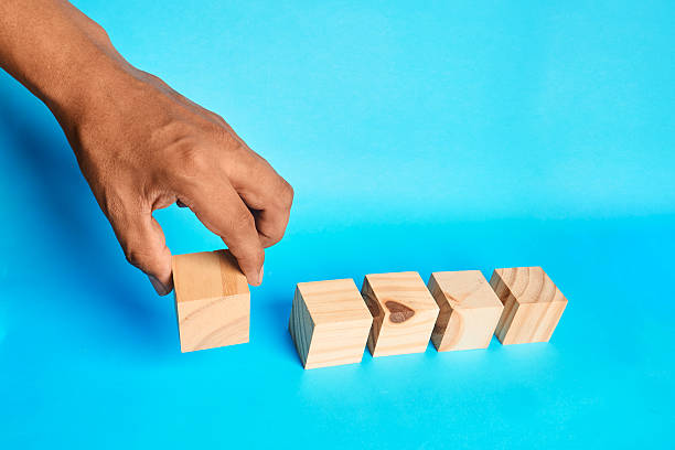 istock Placing the first cube in a series, portraying structure formation, orderly planning, and the beginning of a systematic process. 2243510940