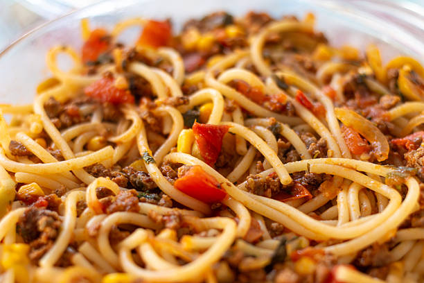 Delicious homemade pasta with minced meat, tomatoes, and vegetables in a glass bowl.