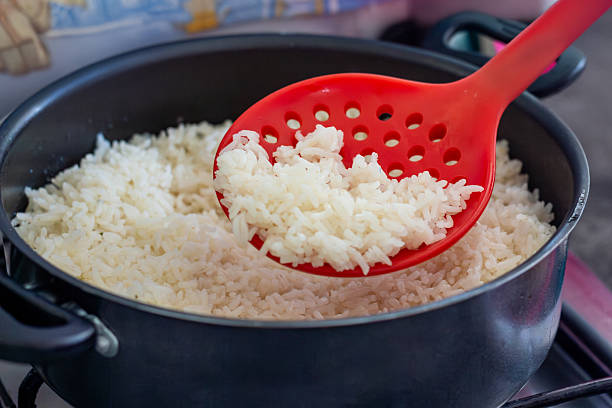 istock Cooked white rice in a pot with a red slotted spoon in a kitchen setting. 2243511895