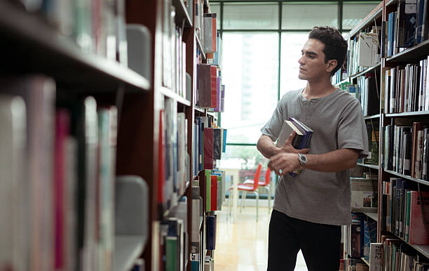 istock A young man stands between the shelves of a library 2243516443