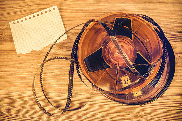 Old Film Reels and Blank Paper on a Wooden Table closeup