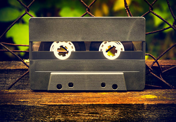 Old Audio Tape Cassette on the Old Wooden Plank and Rusty Metallic Grid outdoor closeup