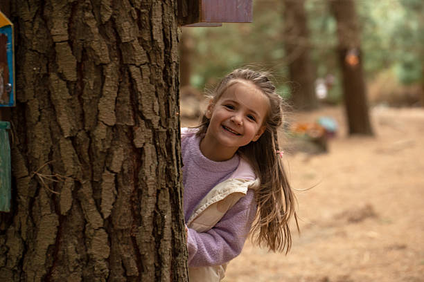 Portrait of a girl hiding behind a tree at the park