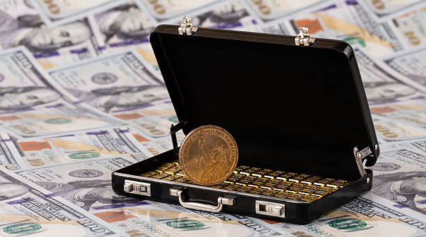 istock A suitcase with gold bars against a background of US $100 bills 2243531708