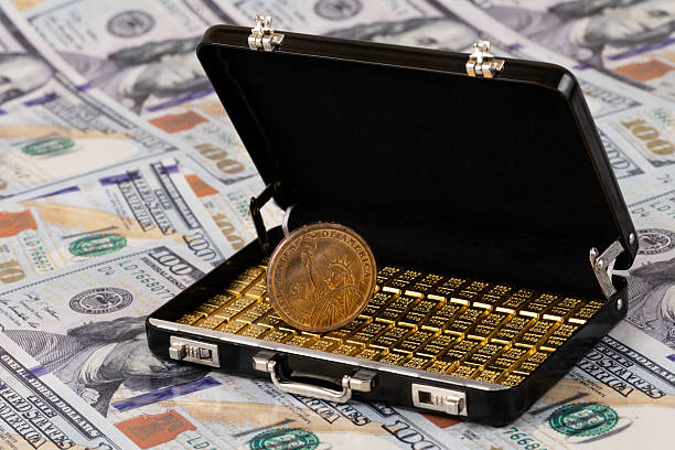 istock A suitcase with gold bars against a background of US $100 bills 2243531709
