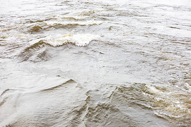 Background view of a turbulent river surface during the flash flood season, causing flooding of agricultural areas in rural Thailand.