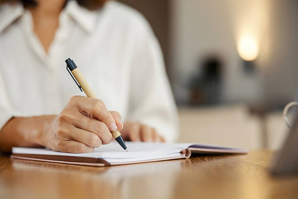 istock Woman writing notes in notebook on wooden desk 2243537659