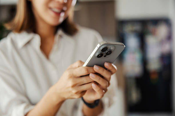 istock Woman holding smartphone and texting in bright kitchen 2243537700