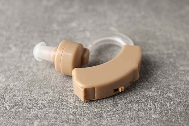 Hearing aid on gray textured background, close up