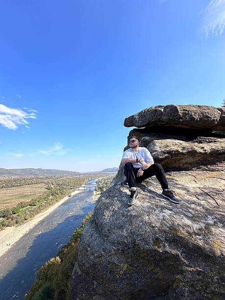 istock Man Sitting on Cliff Overlooking River and Valley 2243558747