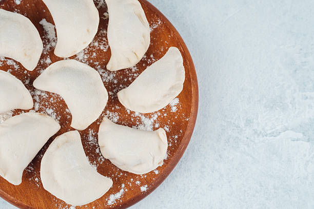 istock Homemade dumplings arranged on a wooden plate with flour backdrop 2243562142