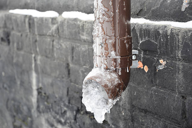 istock A frozen roof gutter drainpipe is completely filled with ice. Frozen rain gutter pipe. 2243563784