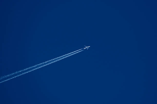 istock Airplane in the blue sky with white contrail. 2243571734