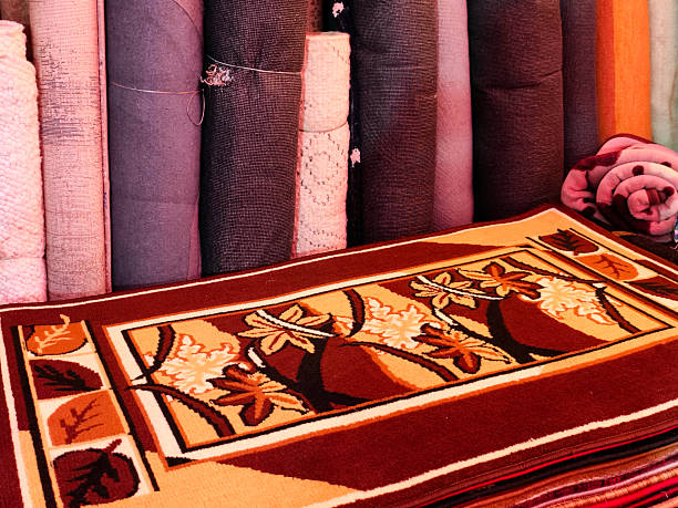Stack of multicolored quality rugs at carpet shop, Carpets variety selection rolled up rugs shop store.