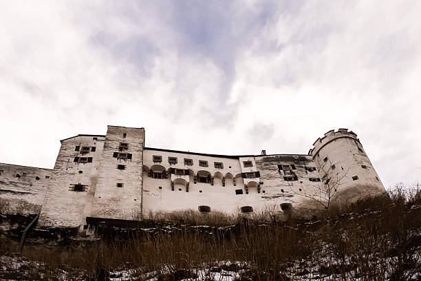 Salzburg, Austria - January 04, 2015 - Majestic medieval fortress overlooking winter landscape under cloudy sky.