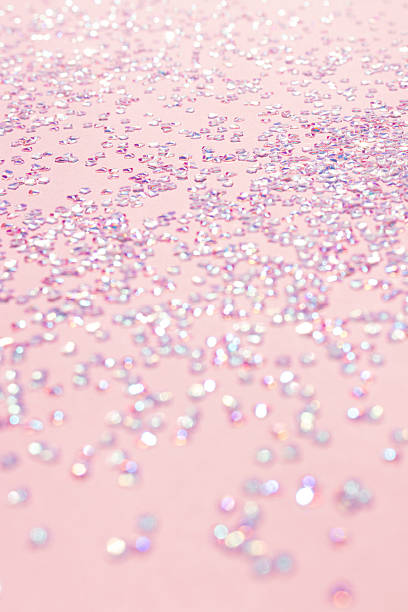 istock Shiny silver crystal confetti scattered on a pink background. 2243574960