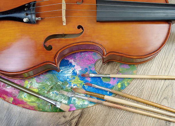 istock violin, brushes and palette on a wooden background. 2243576646