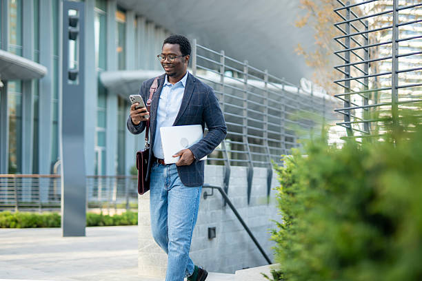 istock Young businessman walking in city while using phone 2243577855